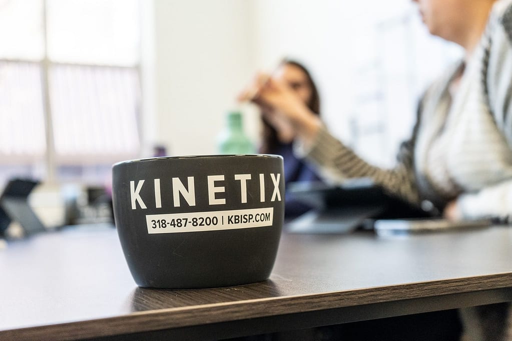 Kinetix branded mug on table in conference room